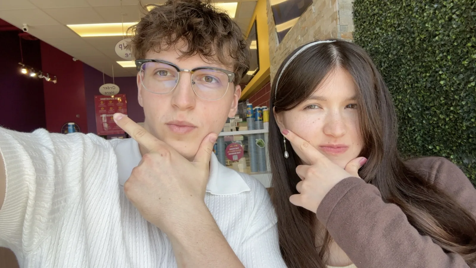 Two of us pulling the same finger-to-cheek pose in a smoothie shop